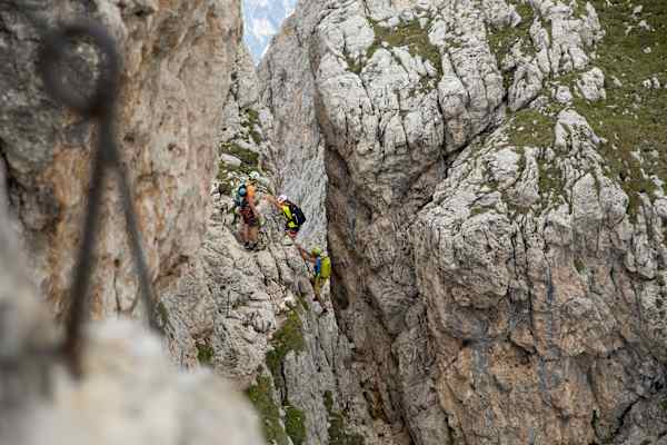 Drei Bergsteiger in steiler Passage des Masaré Klettersteigs in den Dolomiten