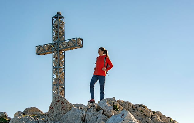 Frau steht am Gipfelkreuz der Rotwand, Eggental