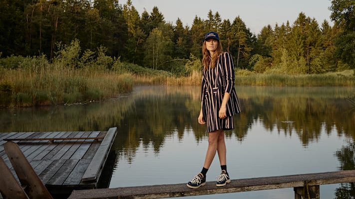 Eine Dame in Gestreifter modischen Kleidung am See auf einem Holzpfad.