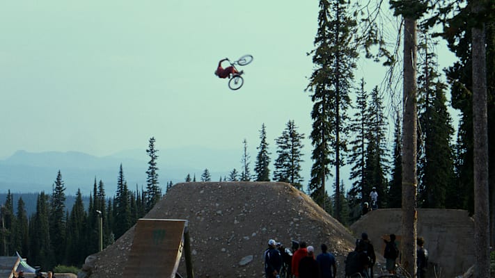 Nicholi Rogatkin fährt mit den Bike eine Rampe in der Natur hoch.
