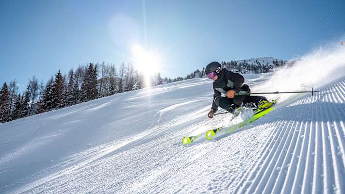Eine Skifahrerin fährt eine perfekt präparierte Piste im Skicircus Saalbach-Hinterglemm-Leogang-Fieberbrunn.