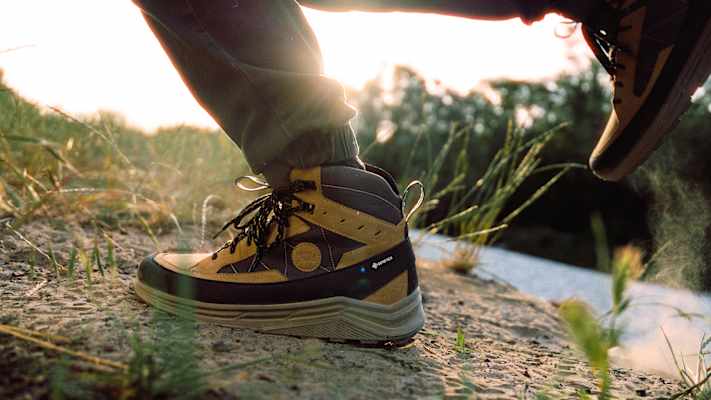 Nahaufnahme eines Hanwag Rotpunkt Light Mid GTX Wanderschuhs auf unbefestigtem Weg bei Sonnenuntergang – robuster, wasserdichter Outdoor-Schuh mit GORE-TEX-Membran.