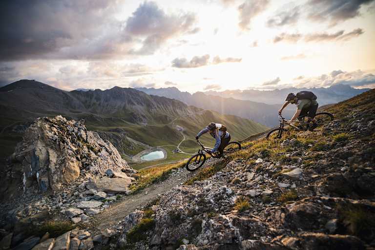 Mountainbiker fahren in eindrucksvoller Gebirgslandschaft bergab