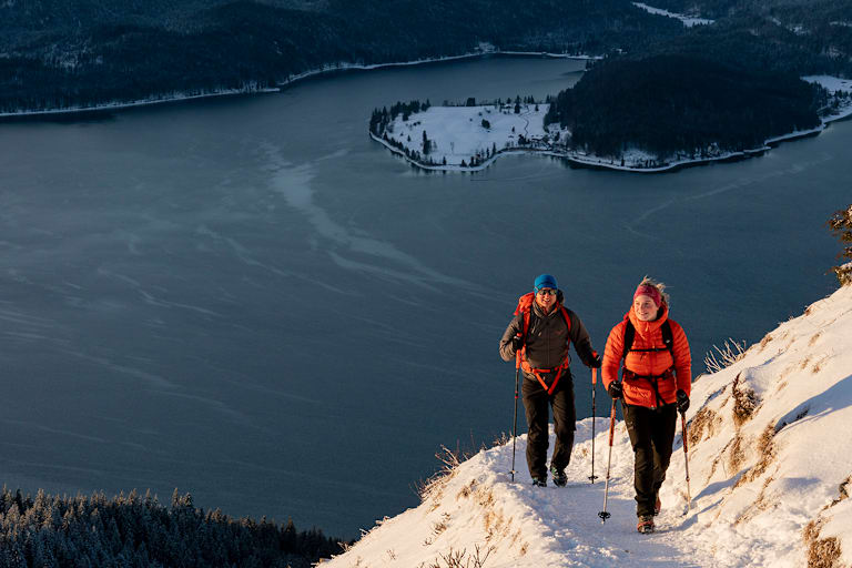 2 Personen gehen auf den Berg wandern im Winter mit Winterkleidung.