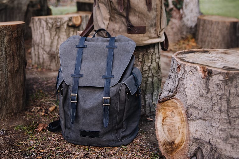 Der große Wanderrucksack von Servus in Grau in der Natur zwischen Baumstämme.
