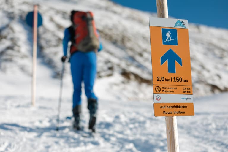 Das Pistentourenleitsystem des Landes Tirol mit orangen Hinweisschildern zeigt den sicheren Weg nach oben.