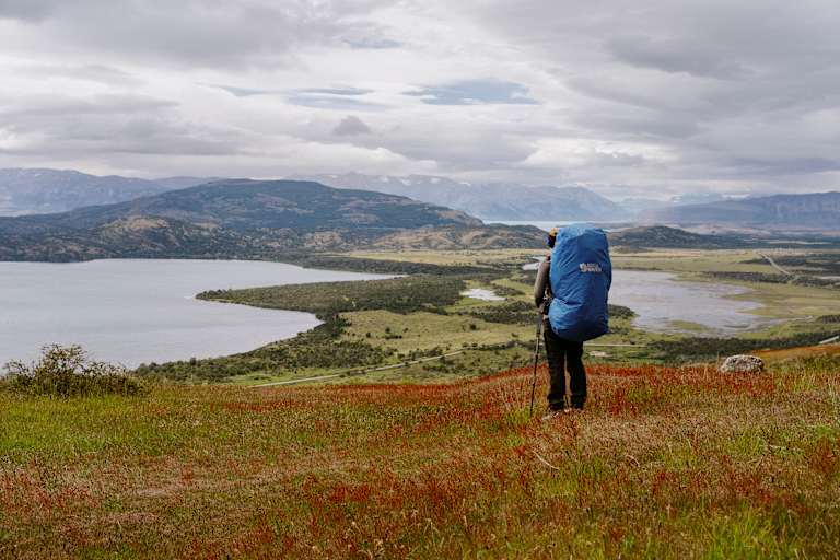 Wanderer steht in Patagonien inmitten einer weiten Landschaft und blickt in die Ferne