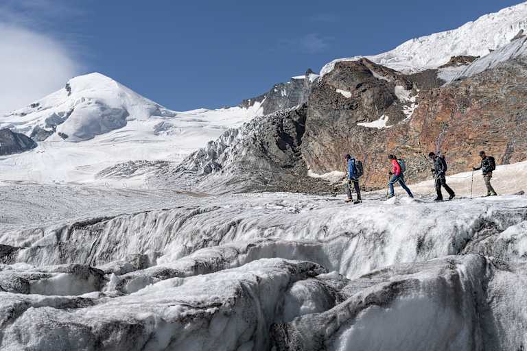 Vier Wanderer unterwegs auf einem Gletscher im Saastal.