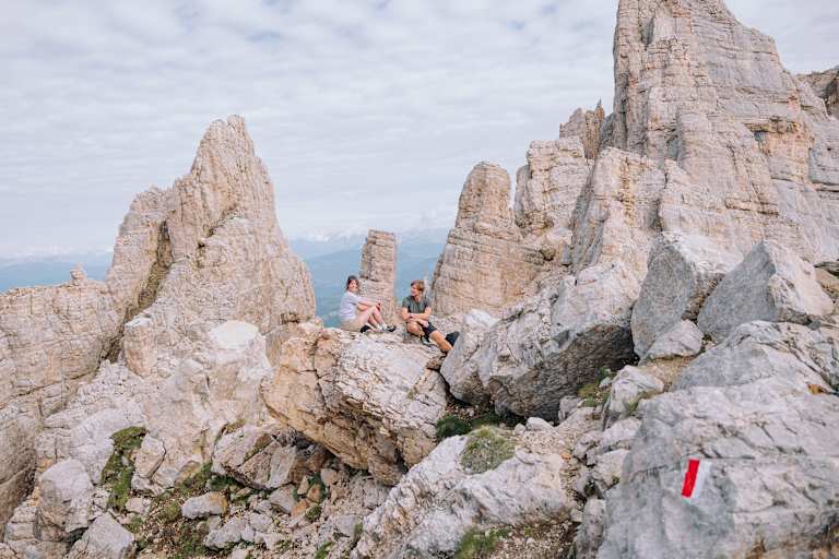 Eine Frau und ein Mann sitzen auf einem Felsen im Eggental.