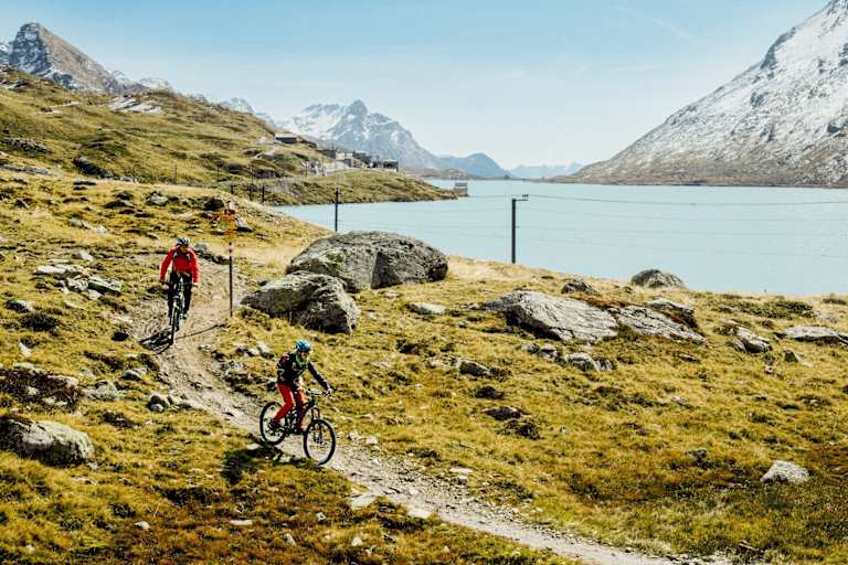 Mountainbiker fahren neben einem See.