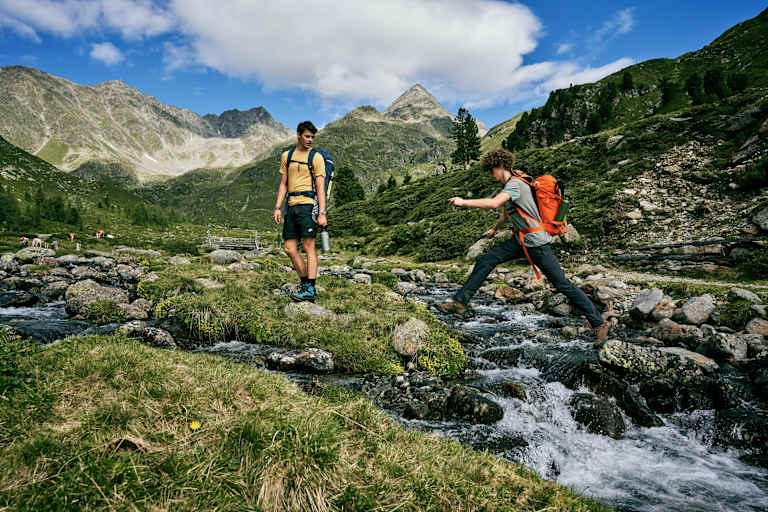 Person springt über Bergbach