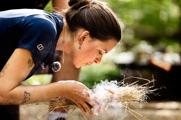 Frau macht Feuer bei Survival Camp