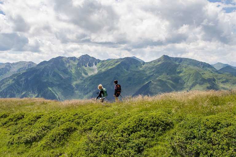 Zwei Frauen spazieren eine begrünte Hügelspitze entlang.
