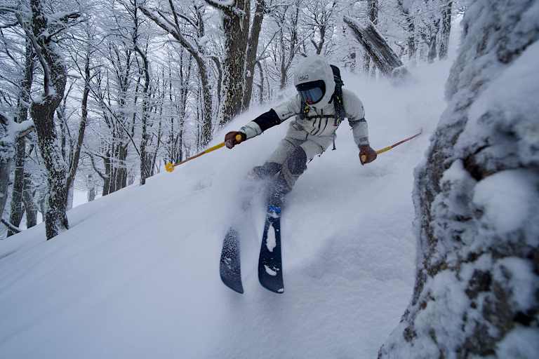 Freerider im Tiefschnee zwischen winterlichen Bäumen.