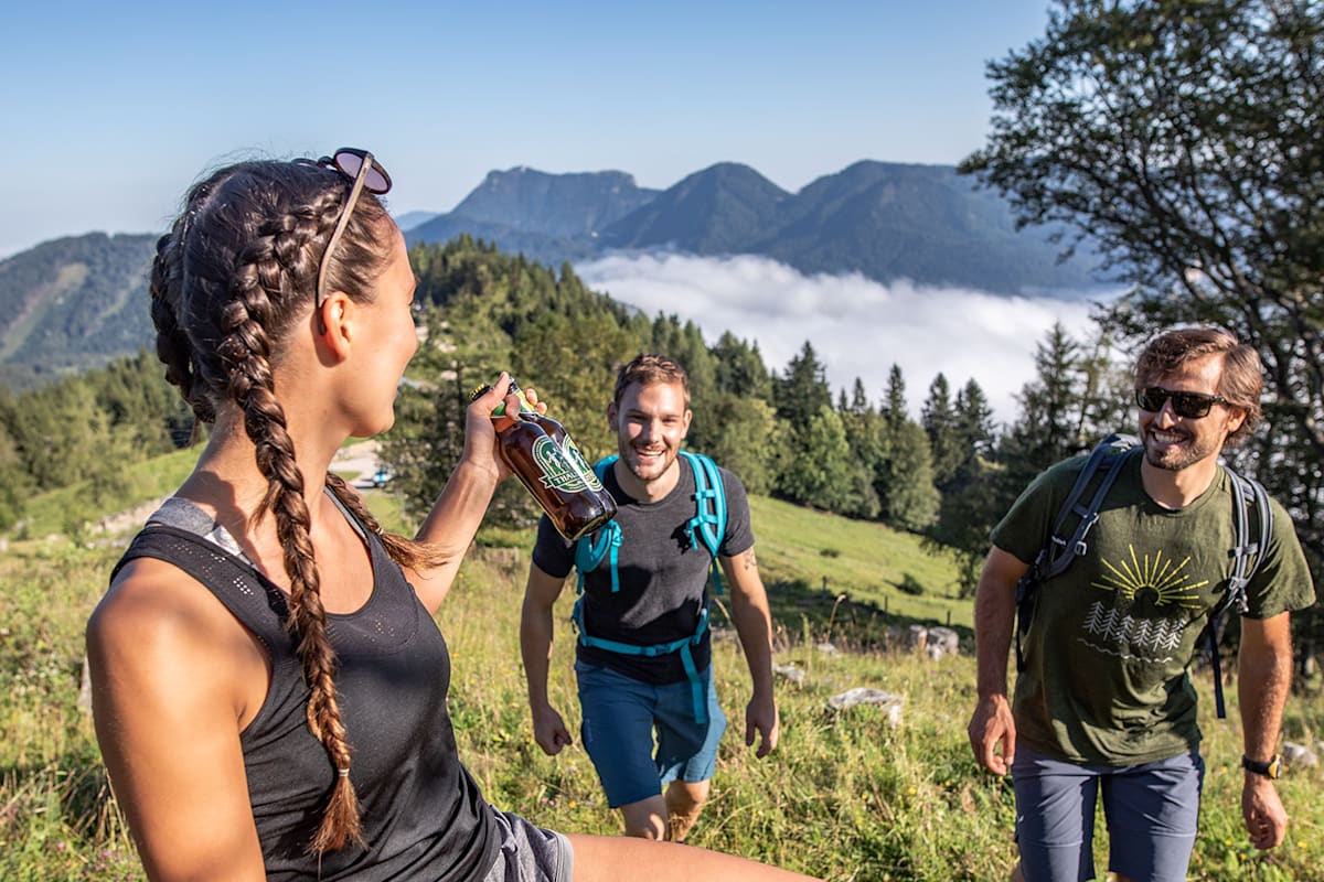Ein Bier in der Hand einer Frau auf der Alm.