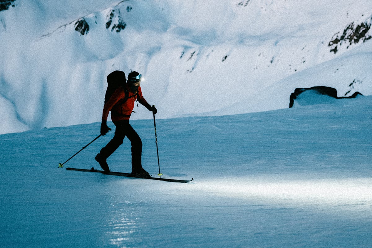 Ein Skifahrer mit einer starken und guten Lampe auf einem Berg in der Nacht.