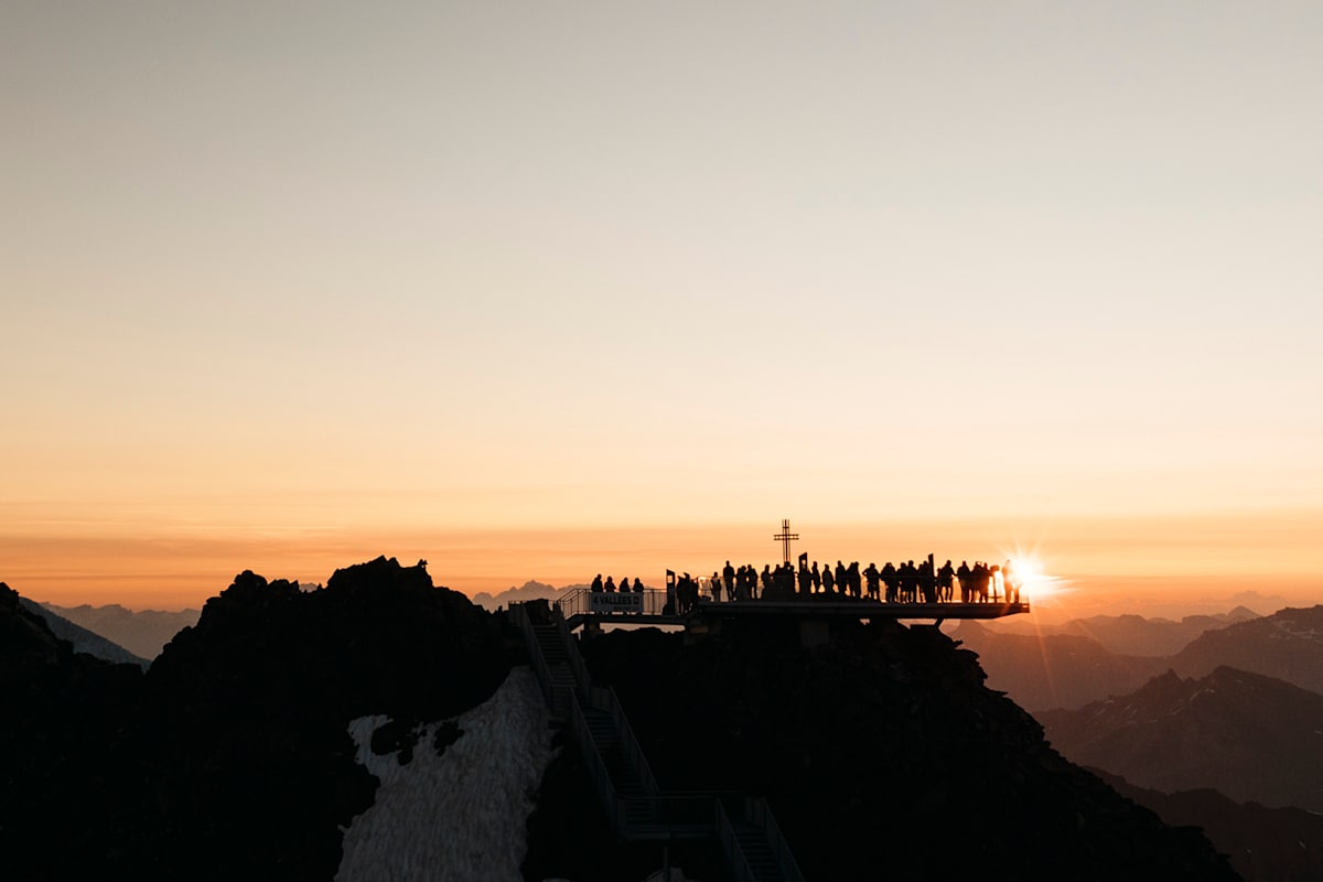 Eine Gruppe von Menschen auf dem Berg Mont Fort schauen sich den Sonnenaufgang an.