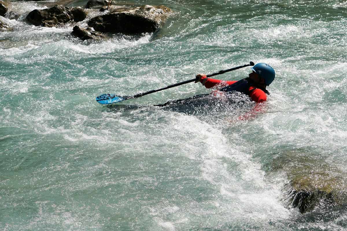 Mann im Wildwasser mit einer Weste mit Prallschutz