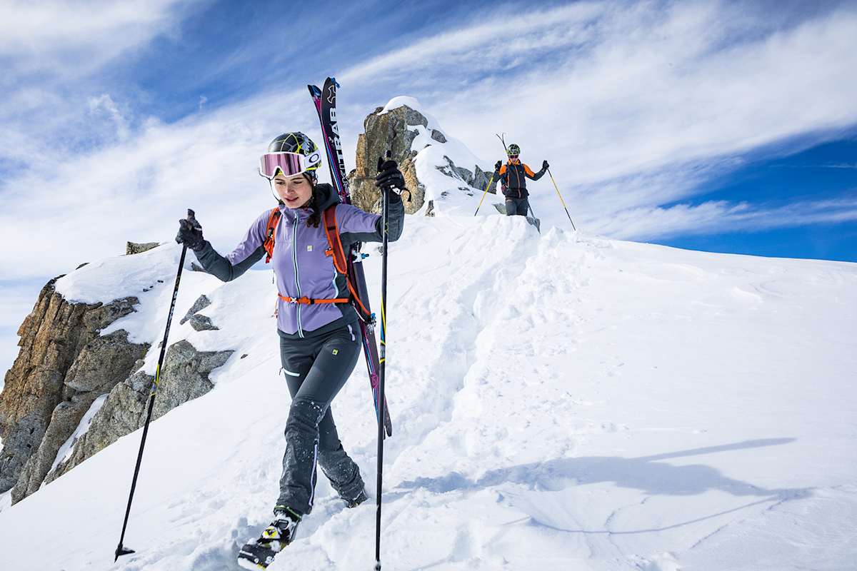 zwei skifahrer auf dem berggipfel am weg nach unten