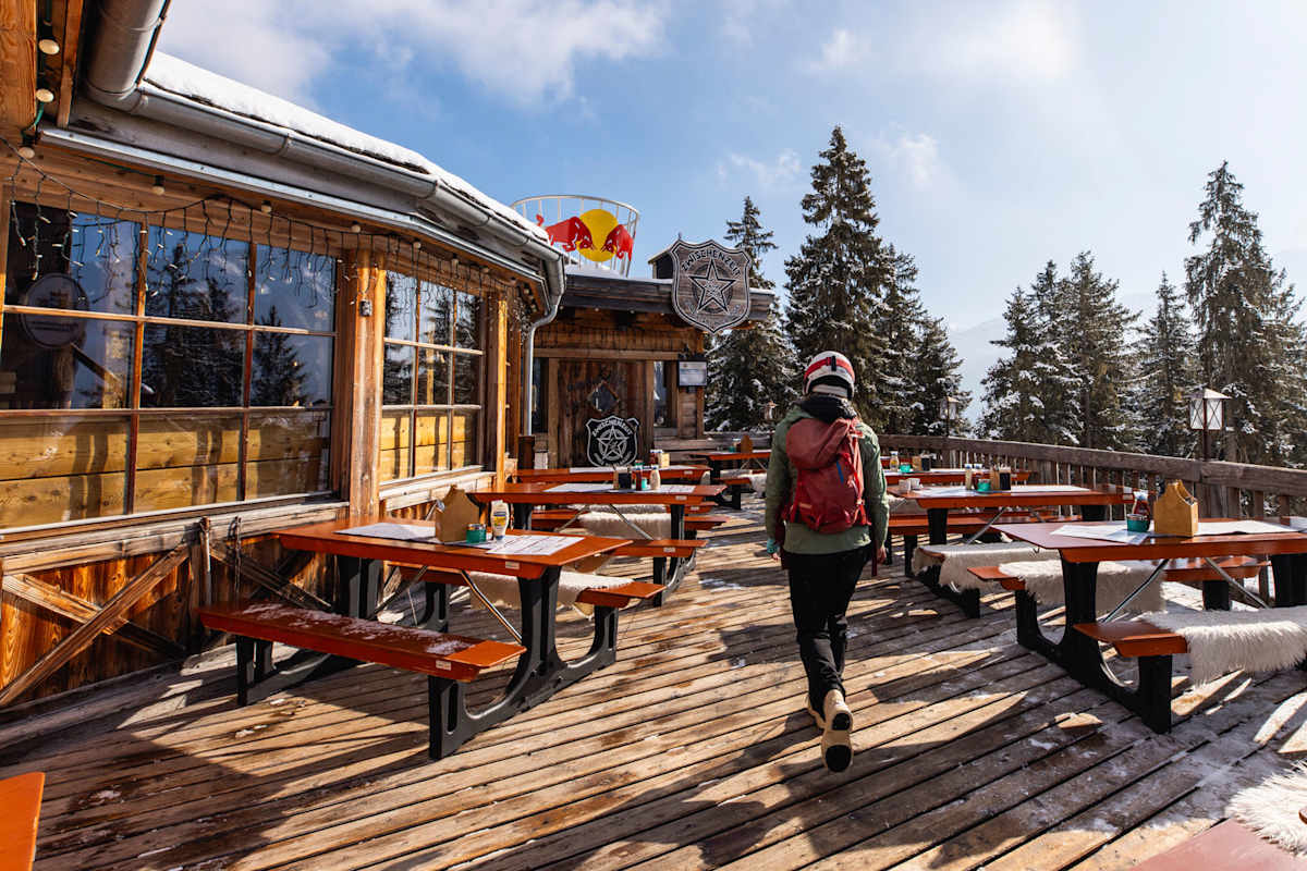 Frau geht in Skihütte hinein im Winter in den Alpen.