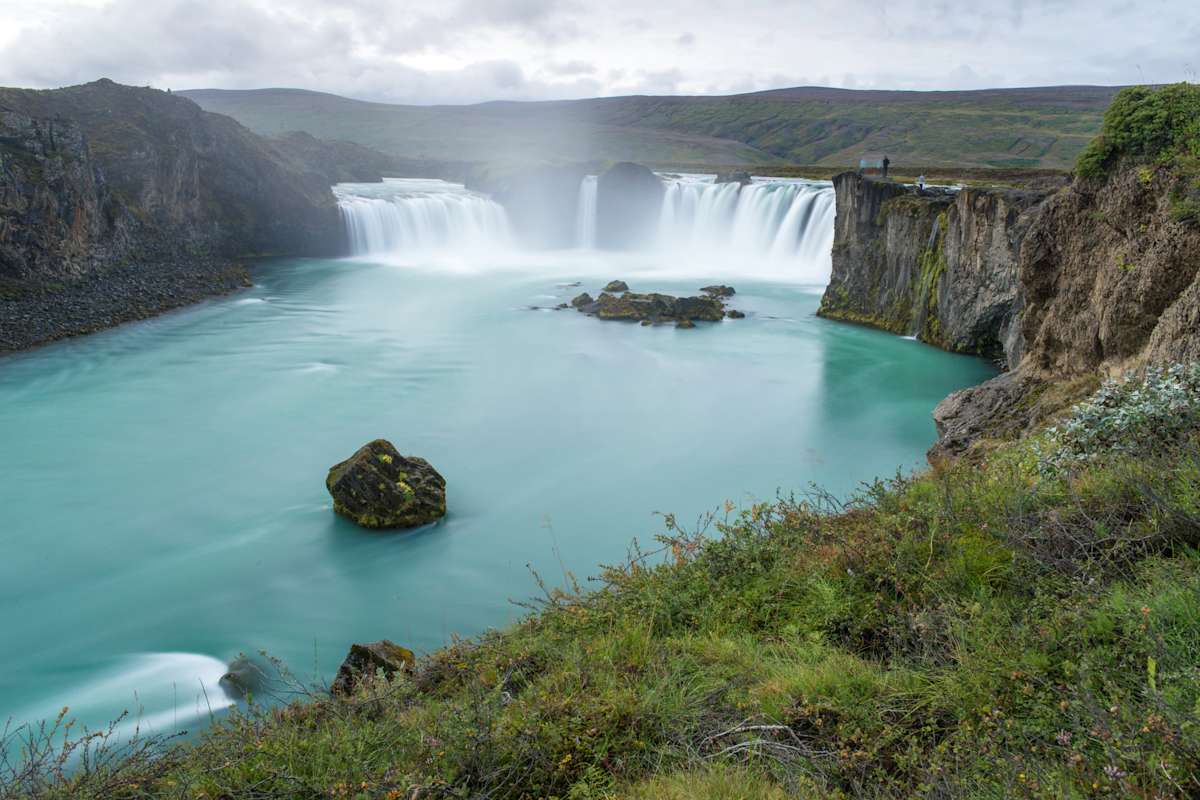 Der 158m breite Godafoss mit hellblauem Wasser und Wasserfall in karger Gesteinslandschaft