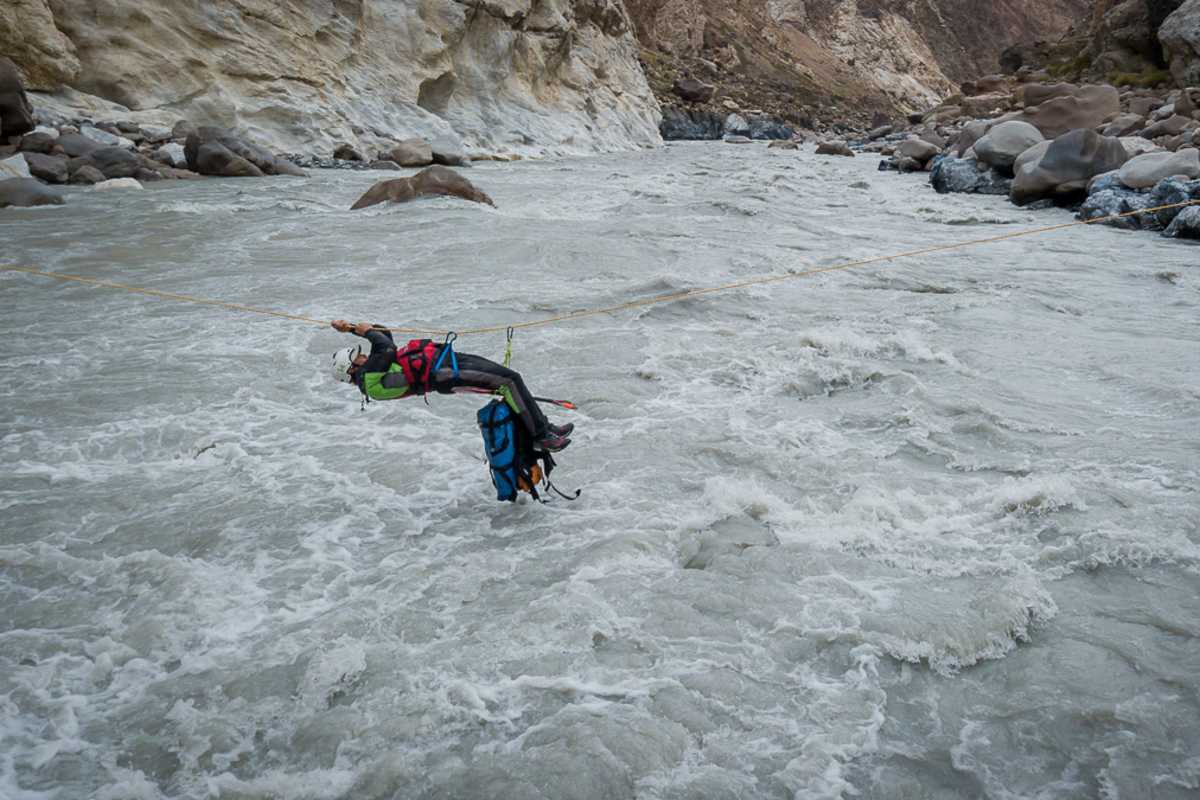 Arian überquert die starke Strömung mit Hilfe der von uns installierten Seilrutsche.