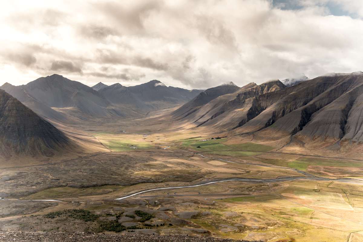 Wenig besiedelte Berge unter bewölktem Himmel und landwirtschaftlichen Flächen