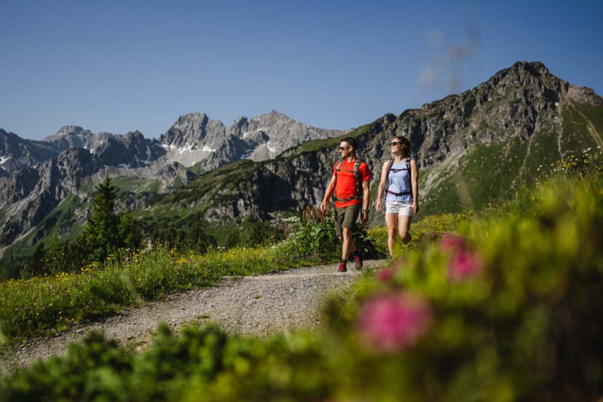 Zwei Wanderer schlendern über einen aussichtsreichen Höhenweg.