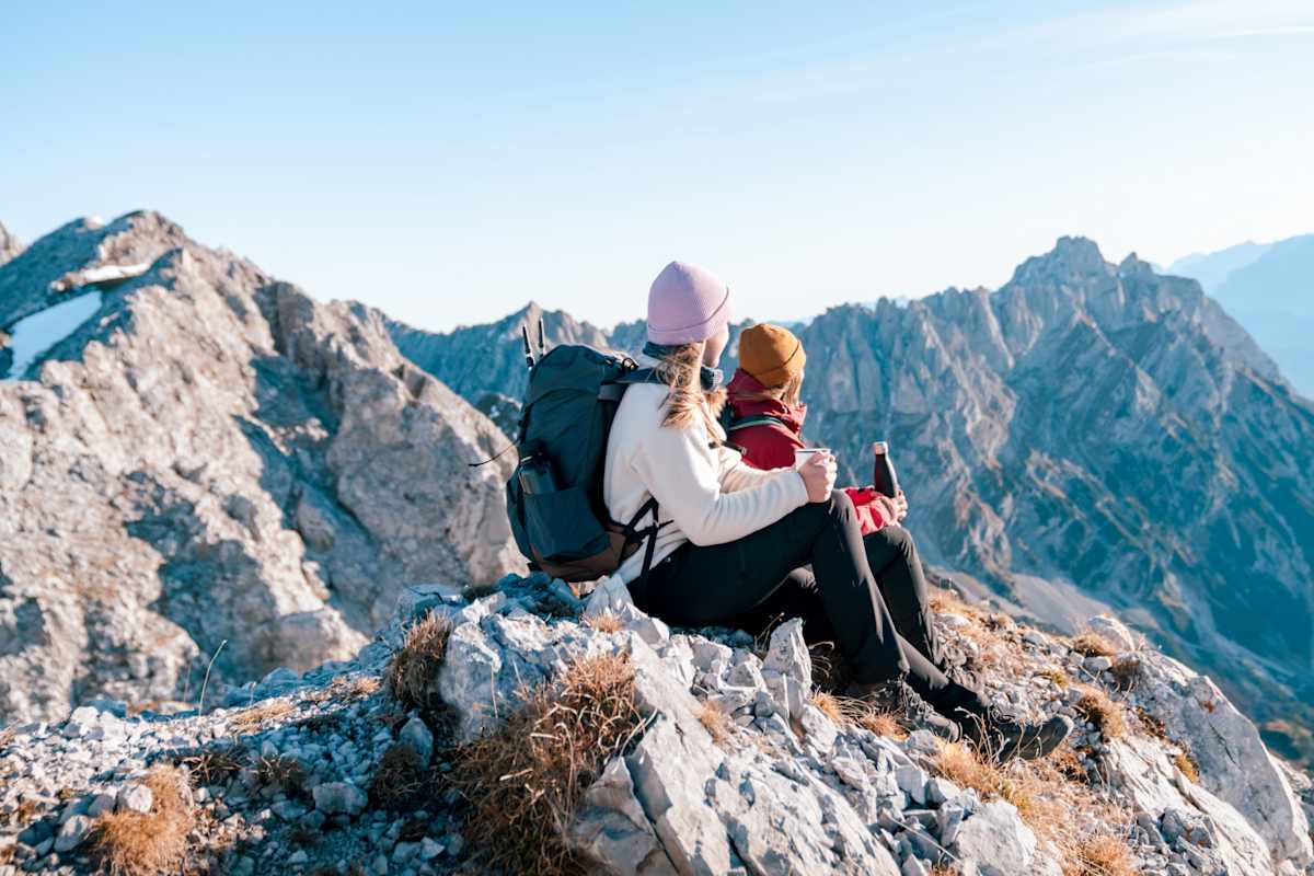 Zwei Mädchen sitzen am Gipfel und genießen eine Pause.