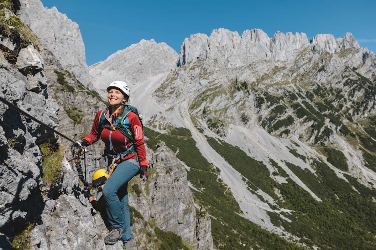 Ein junges Mädchen steigt einen Klettersteig empor.