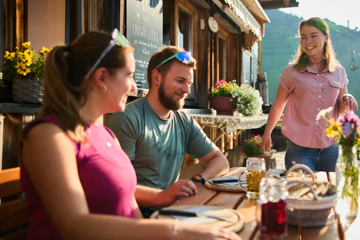 Zwei Wanderer jausnen auf einer Alpe.