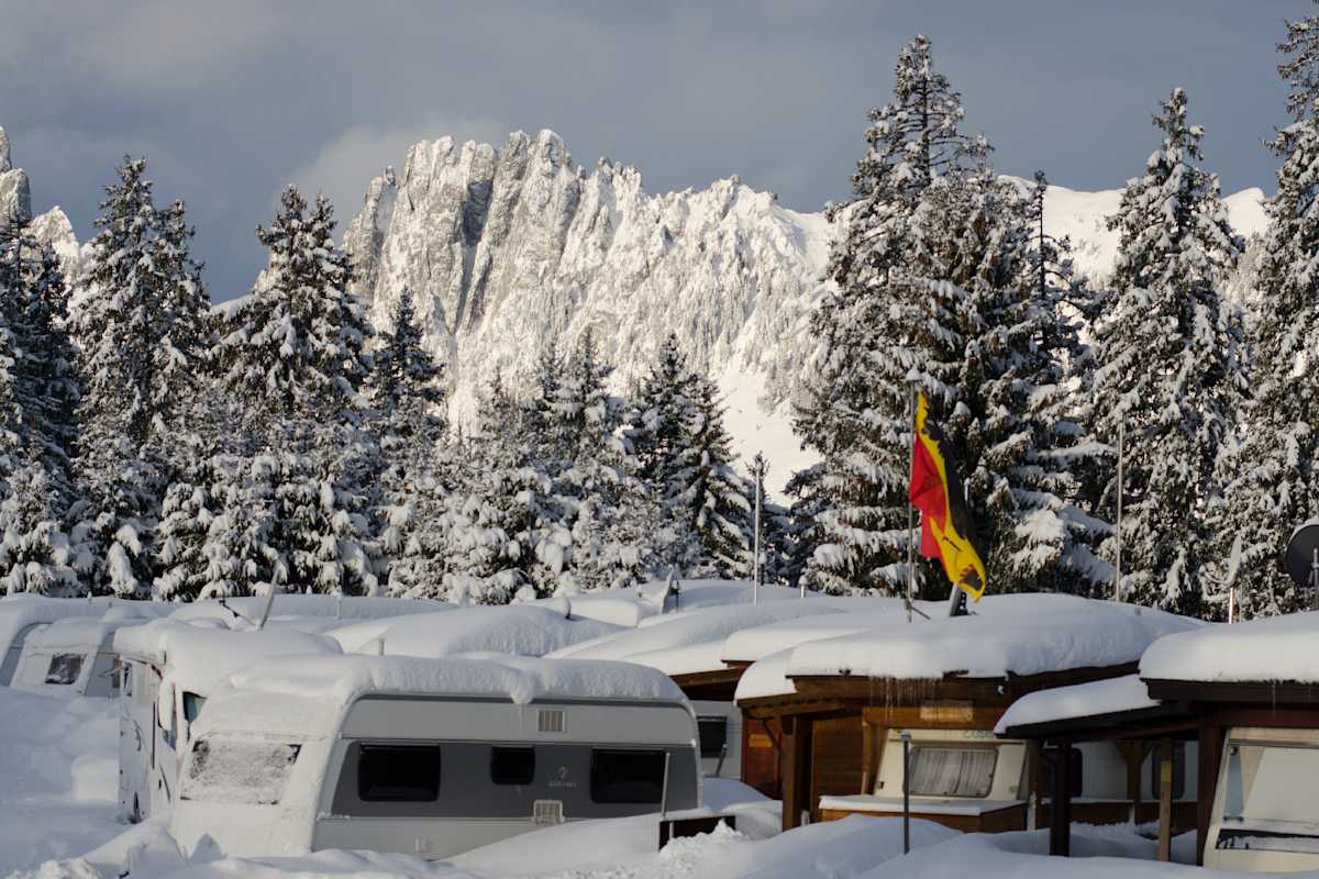 Auf dem Camping Jaunpass im Berner Oberland stehen die schneebedeckten Wohnwagen im Winter direkt vor der imposanten Bergkulisse der Gastlosen.