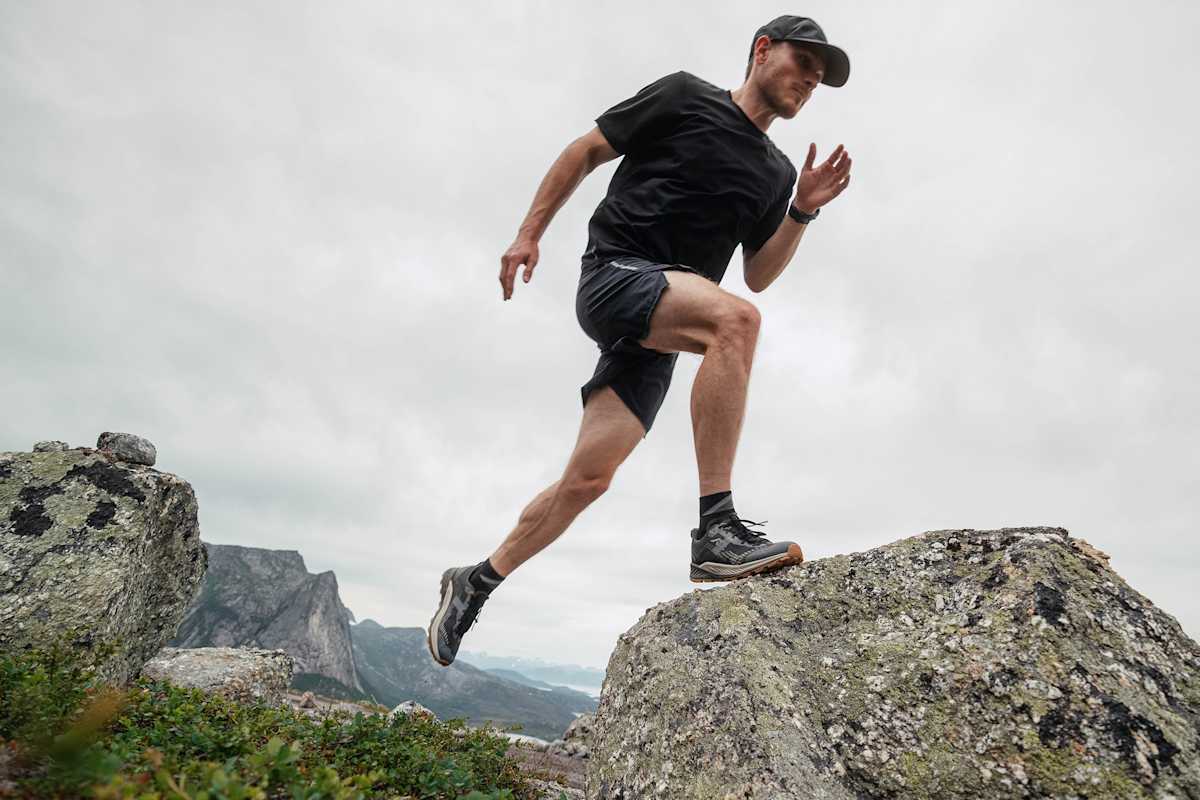 Ein Trailrunner springt mit einem Fuß auf einen Stein im Gebirge. Die Schuhe, die er dabei trägt sind die neuen LOWA AMPLUX 2 GTX.