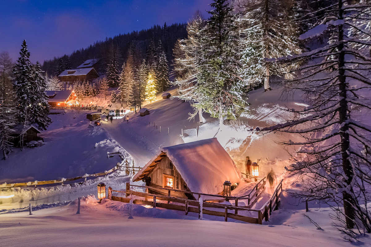 Ein mit Lampen erleuchtetes Bergdorf in der Nacht.