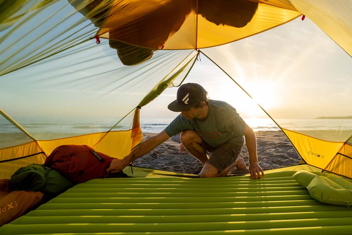 Ein Camper legt seine Matte im Zelt auf.