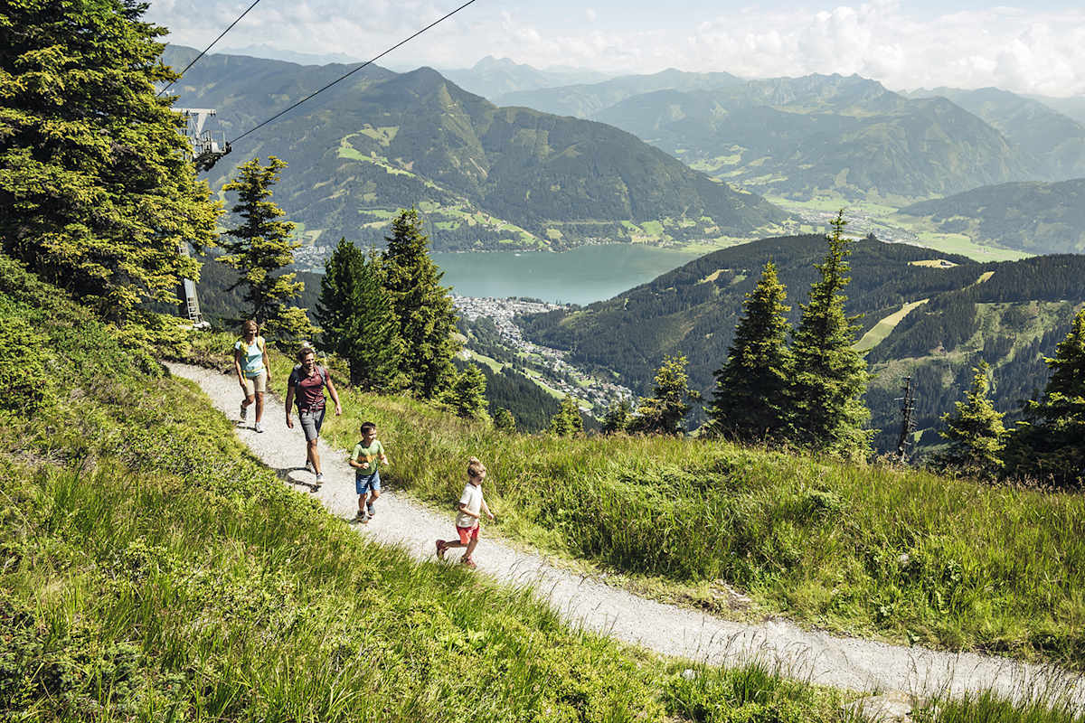 Ein Mann und eine Frau wandern mit ihren zwei Kindern auf die Schmittenhöhe.