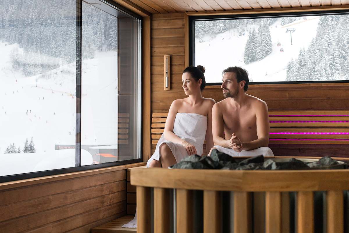 Eine Frau und ein Mann sitzen in der Therme in Gastein und blicken auf die Schneelandschaft.