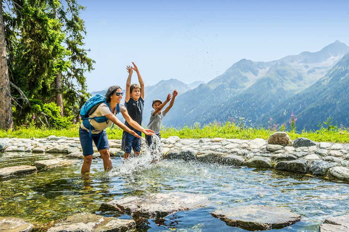 Eine Mutter und zwei Kinder planschen im Sunny Mountain Erlebnispark in Kappl.