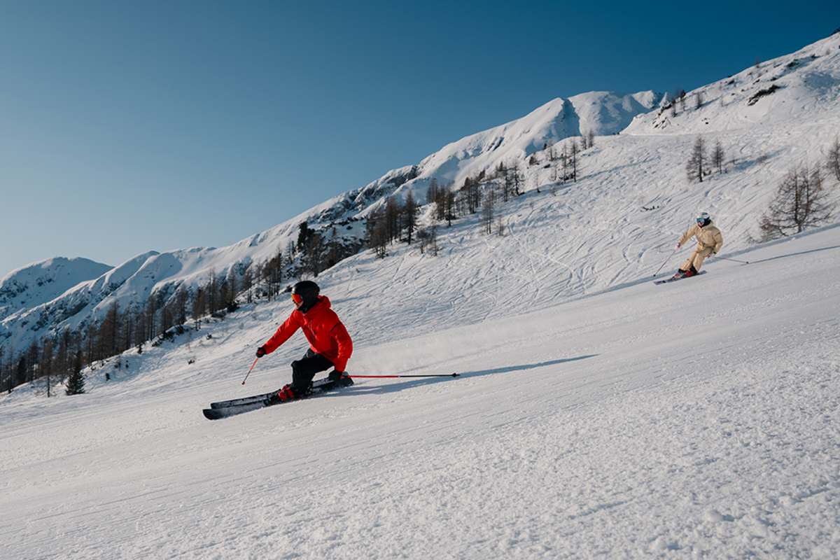 Zwei Skifahrer fahren eine perfekt präparierte Piste am Zauchensee hinunter.
