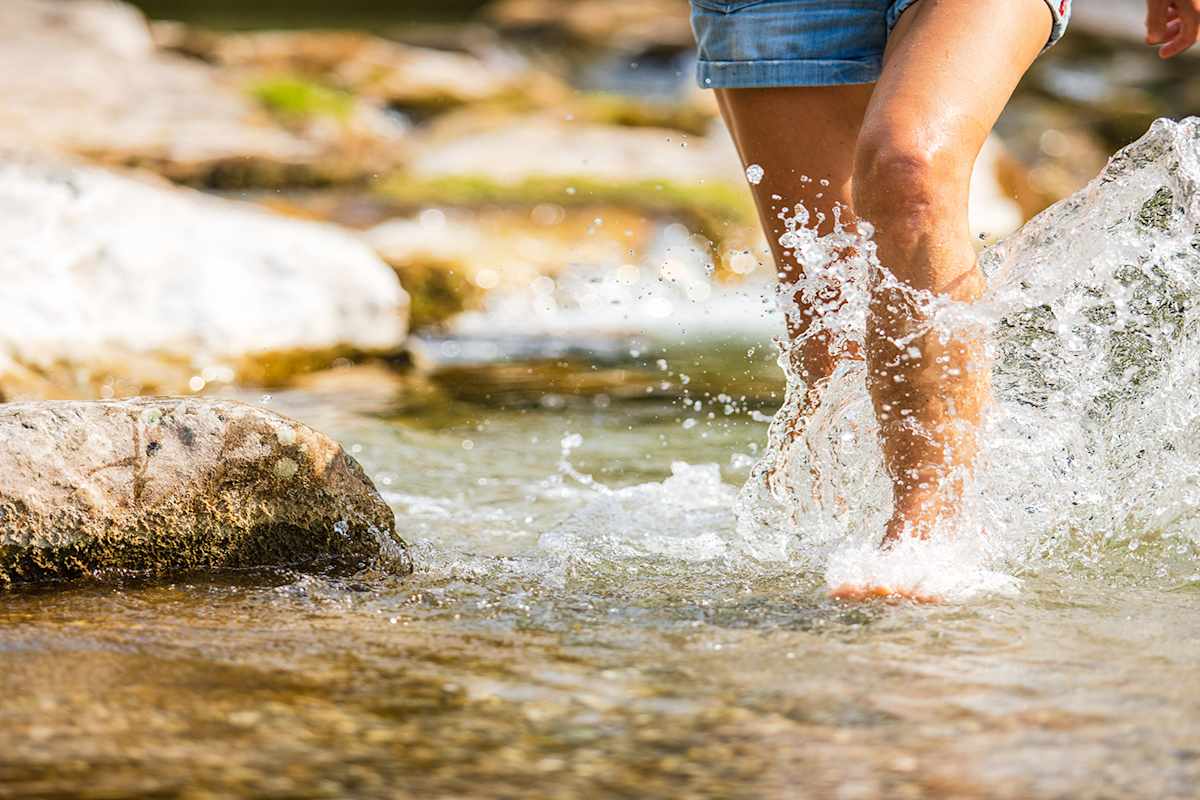 Füße durchqueren einen Fluss
