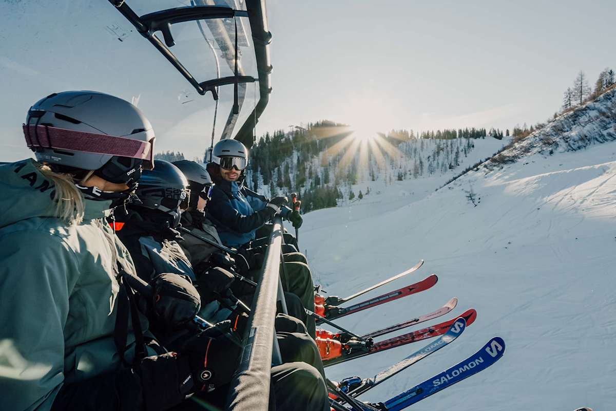 Eine vierköpfige Familie sitzt auf einem Sessellift und genießt den Ausbilck.
