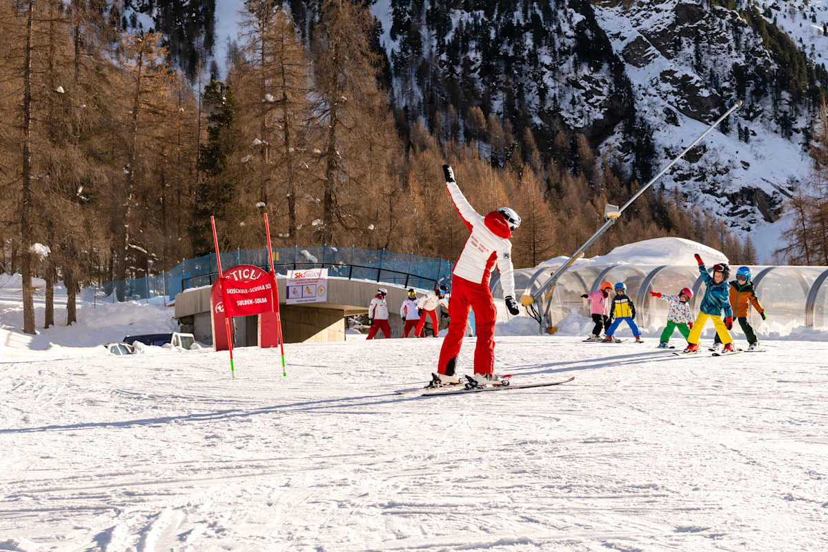Eine Skilehrerin macht mit ihren Schülerinnen und Schülern ein paar Übungen.