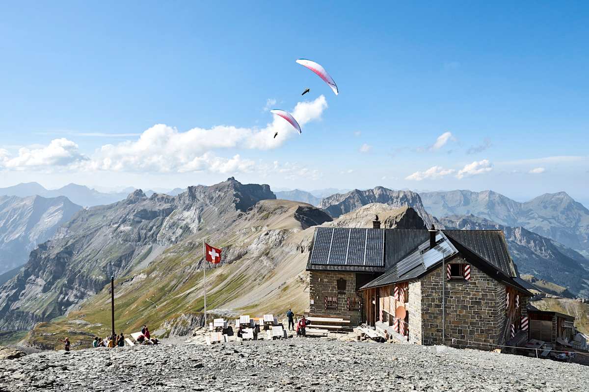 Eine Hütte mit zwei Paragleitern im Hintergrund.