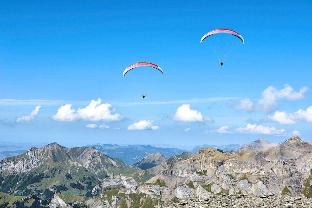 Zwei Gleitschirmpiloten in luftiger Höhe.