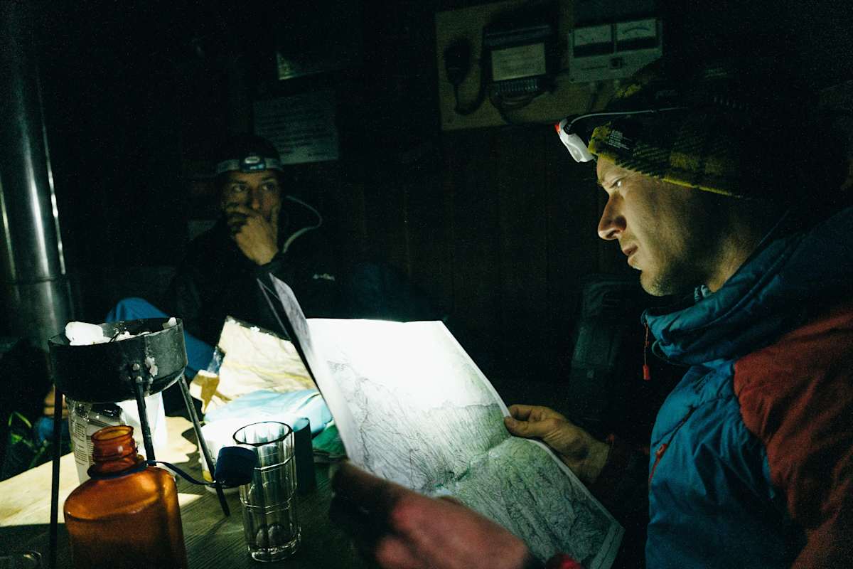 Mann mit Stirnlampe schaut auf Wanderkarte