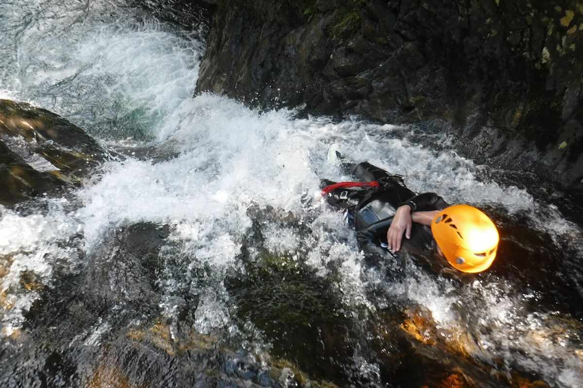 Wasserfall und Schlucht zwischen Felsen mit person beim Abseilen während des Canyonings