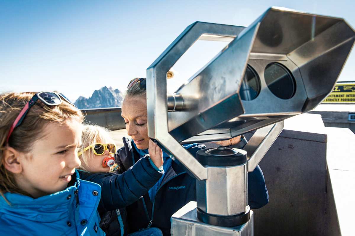Drei Personen vor einem Fernglas.