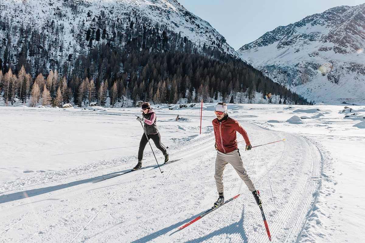 Eine Frau und ein Mann auf ihren Langlaufskiern in der verschneiten Natur Merans.