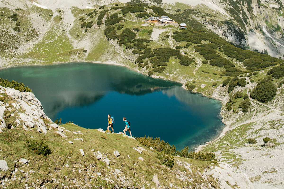 Wanderer am Drachensee in Tirol - im Hintergrund die Coburger Hütte.