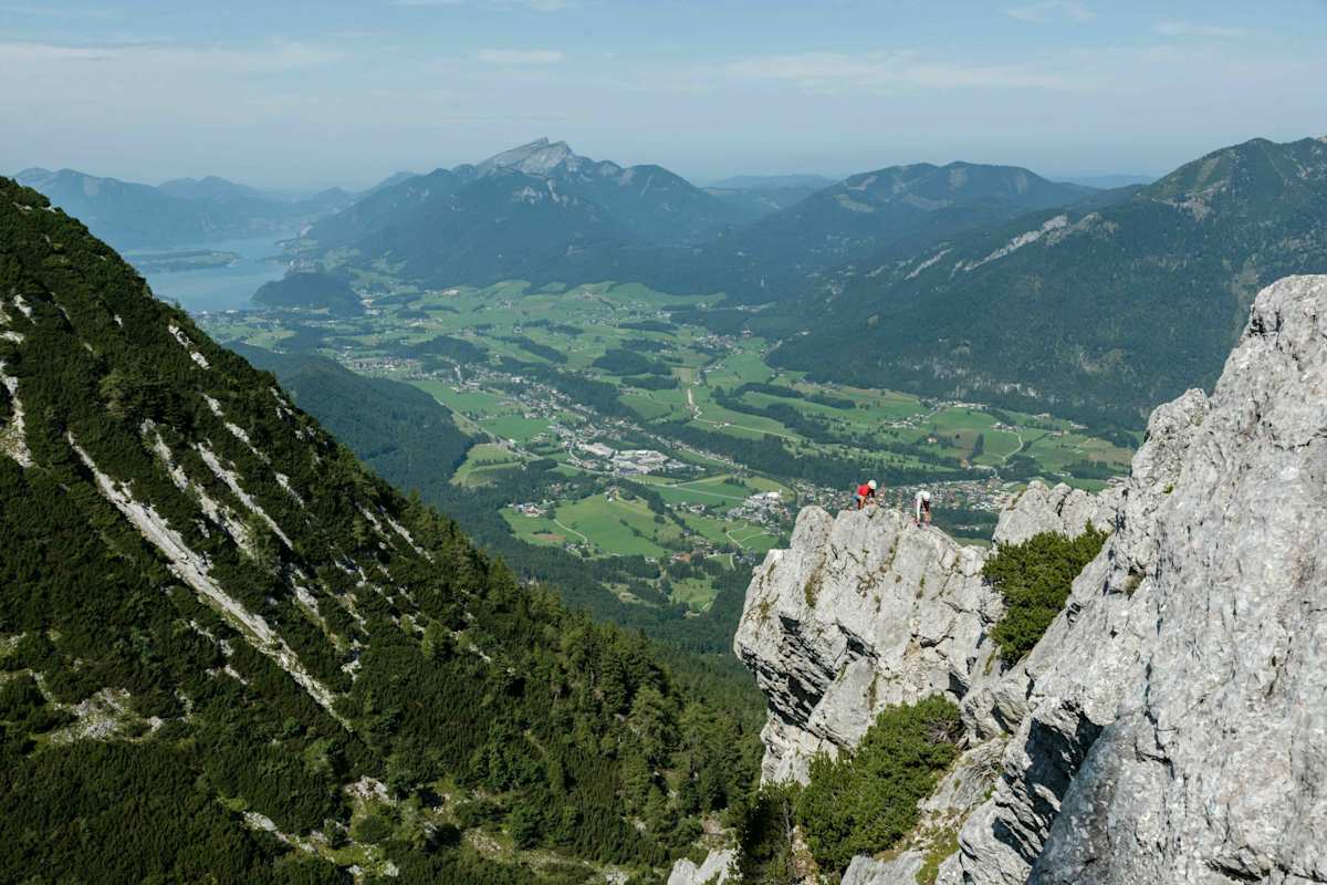 Zwei Kletterer am Katrin-Klettersteig über Bad-Ischl mit Blick auf die umliegende Landschaft und einen See
